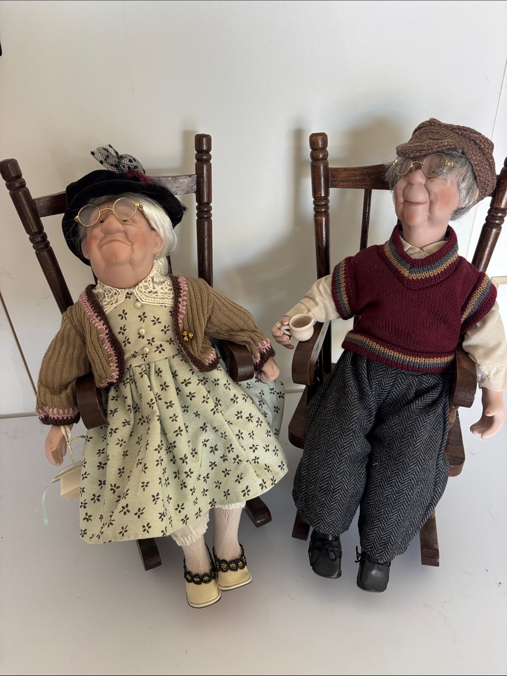 A pair of vintage-style porcelain dolls depicting an elderly couple.
